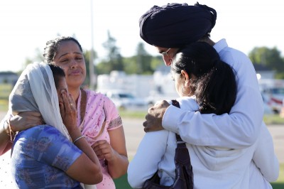 Mourners cry outside the scene of a mass shooting at a Sikh Temple in Wisconsin. The shooter used a legally purchased 9mm handgun in the rampage. (Photo from REUTERS/John Gress)