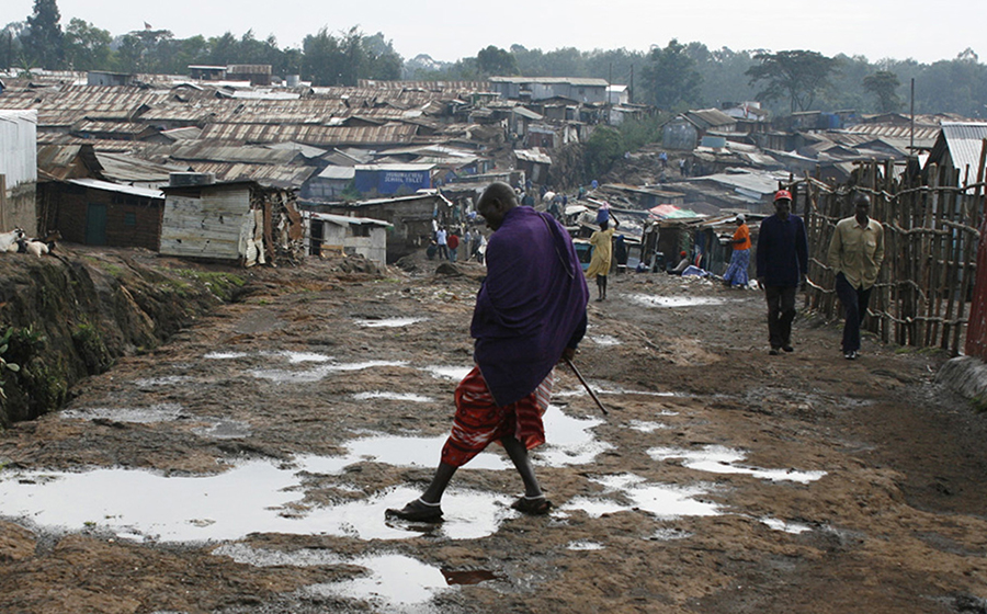 A Masai man cleans his shoe off in a puddle in Kibera. Masai, known to be fierce fighters, are often employed as personal bodyguards inside the slum to walk residents home late at night. (Photo by Alex Stonehill)