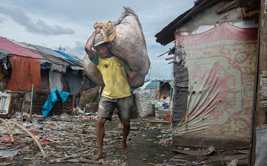 Near Jakarta, Indonesia, a man earns a daily wage picking through the Bantar Gebang landfill for recyclables to sell. Slum dwellers typically live a much more environmentally friendly lifestyle, finding value in what others would waste. (Photo by Branden Eastwood)