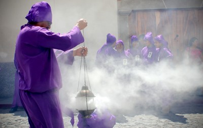 A man releases a potent cloud from his “incensario” filled with myrrh resin and used to "cleanse" the parade route. (Photo by Devin McDonald)