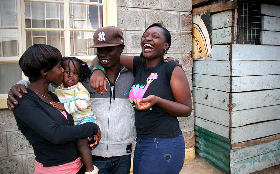 A family, Halima, Richie and Leslie (from left to right), hugs outside of their home in Kibera. Despite lack of access to government services, many residents in Kibera stay because of the strong community and support neighbors. (Photo by Abby Higgins)