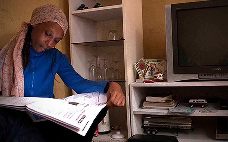 Mariam reads The Ghetto Mirror, a youth-produced newspaper, in her home in Kibera. (Photo by Abby Higgins)