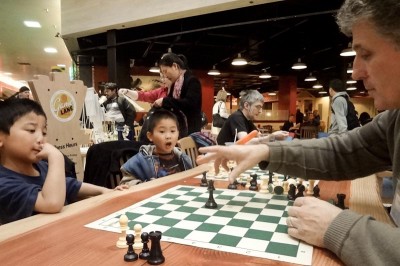 Chess4Life coach Hristo Arabadjiev teaches two newcomers the basics of piece movement. (Photo by Ilona Idlis)