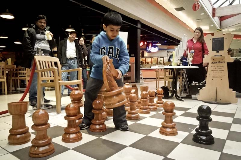 Aavir, 6, plays with the over-sized chess set during “2nd Saturday Family Night” at Crossroads mall. (Photo by Ilona Idlis)
