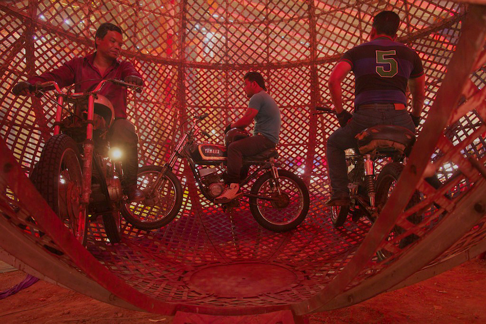Bikers prepare to ride motorcycles inside a metal ball.