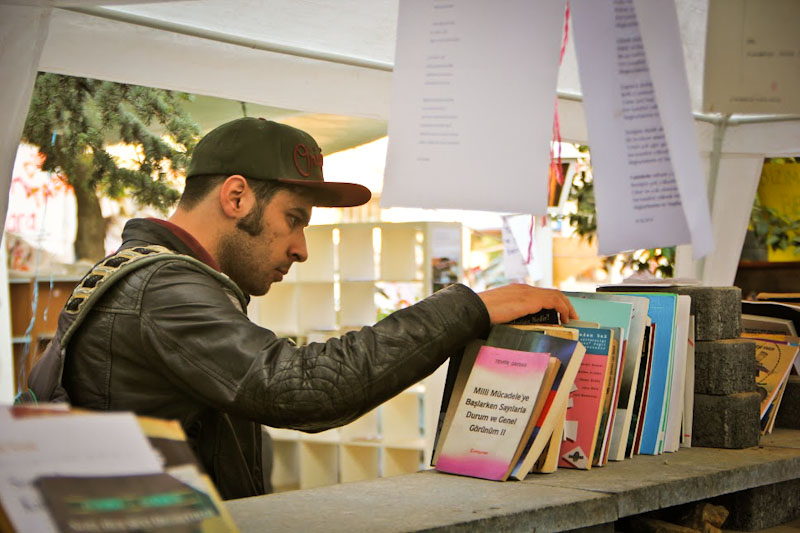 A protester browses through one of the camp’s free libraries where the scope of literature ranges from Marxist theory to trashy American romance novels. (Photo by Christan Leonard)