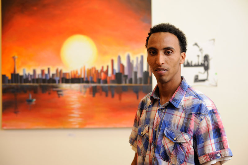 Abraham Tesfelaise, with his painting "Beautiful Dream" at the Downtown YMCA. (Photo by Colleen McDevitt)