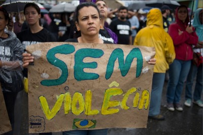 A resident of "Nova Holanda," a shantytown in Rio de Janeirno, holds a sign reading "No Violence" at a memorial for victims killed in a police incursion. (Photo by Nick Wong)