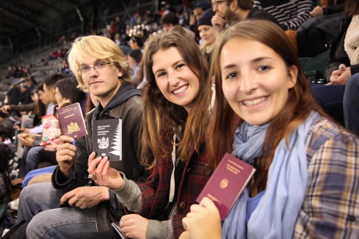 University of Washington international students from The Netherlands, New Zealand and Germany show off their passports at a Mariners to celebrate the first day of class. (Photo by Alex Stonehill)