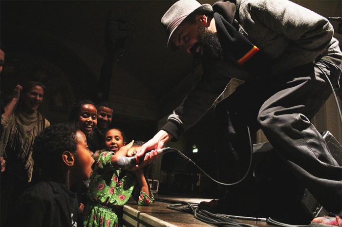 Gabriel Teodros shares the mic with a young fan. (Photo by Aida Solomon)