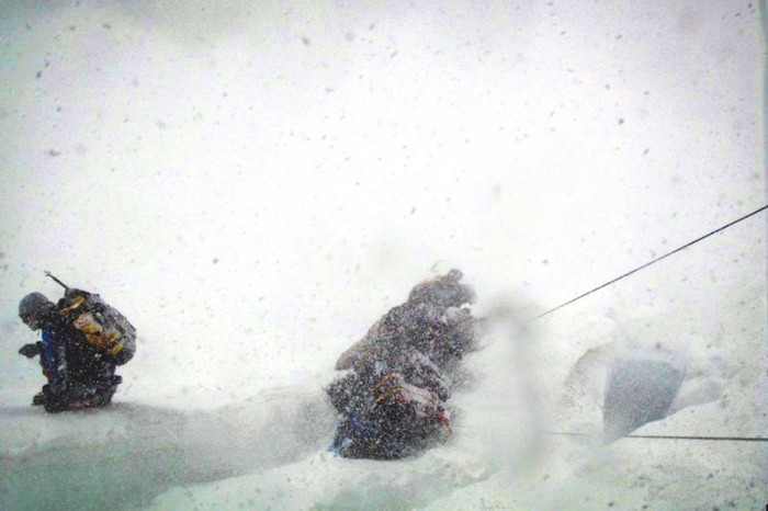 Climbers in the midst of a small avalanche during an Everest ascent. (Photo by Lloyd Smith)
