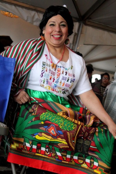 Martha Camarena shows her skirt which reads "Mexico!" Camarena is originally from Guadalajara, Mexico and participates in performances and events with El Centro de la Raza. 