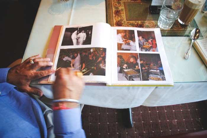 Hanek flips through a photo album of the first orthodox Jewish wedding in Portland catered by Pabla. The album is featured prominently upon entering, titled 'Jewish Wedding with Pabla Indian Cuisine.' (Photo by Anna Goren)