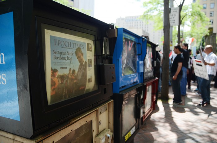 Protesters stand in front of Seattle's City Hall downtown, beside them a newspaper stand displays an article about the sectarian situation unfolding in Iraq. (Photo by Alisa Reznick)