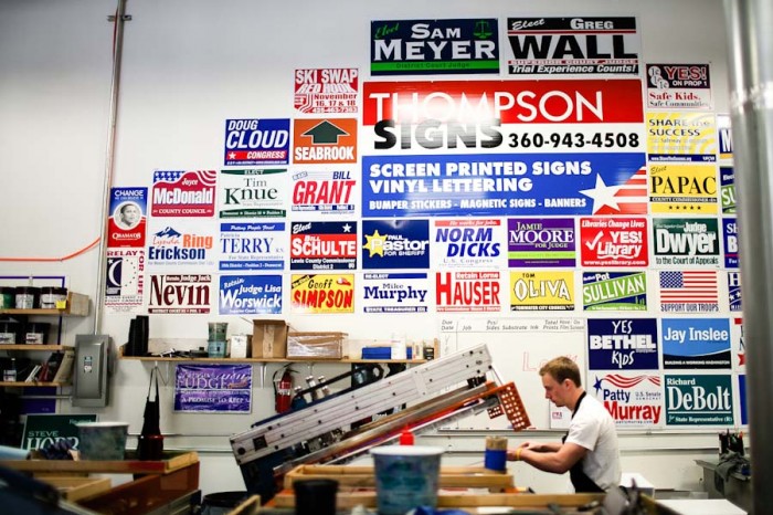 The wall of old signs inside of Thompson Signs' warehouse serves as a visual reminder of the mostly white, male political candidates in the northwest. (Photo by Lucas Anderson / UW Election Eye)