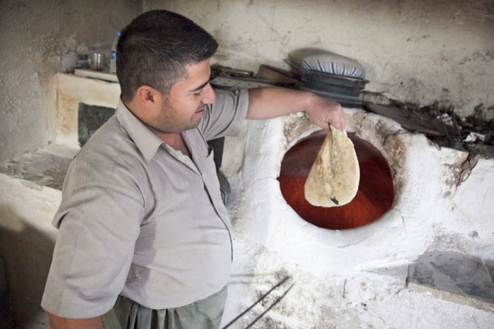 A baker uses a tandoor oven in Iraqi Kurdistan. (Photo by Alex Stonehill)