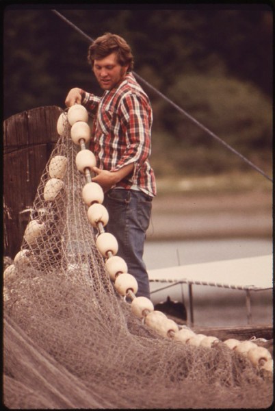 Nick Jerkovich Jr of Gig Harbor works on a seine net for salmon fishing in an archive photo from 1973. (Photo from National Archives/EPA)