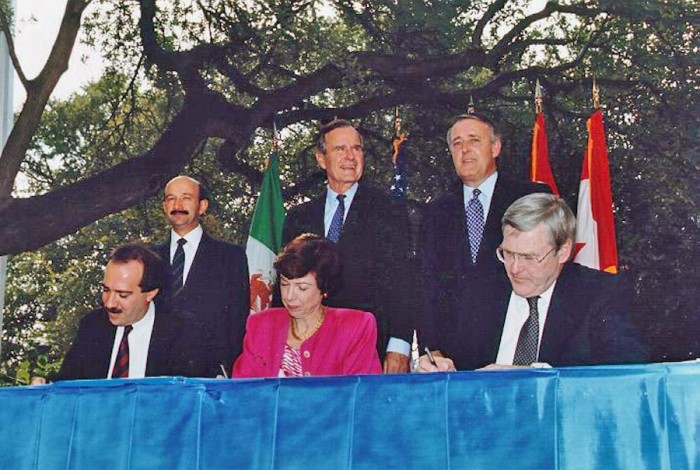 At the NAFTA Initialing Ceremony, in October 1992 , Mexican President Carlos Salinas de Gortari, US President George H. W. Bush, Canadian Prime Minister Brian Mulroney along with trade officials from all three countries. Bill Clinton finalized the negotiations after taking office the next year. (Photo from the George Bush Presidential Library)