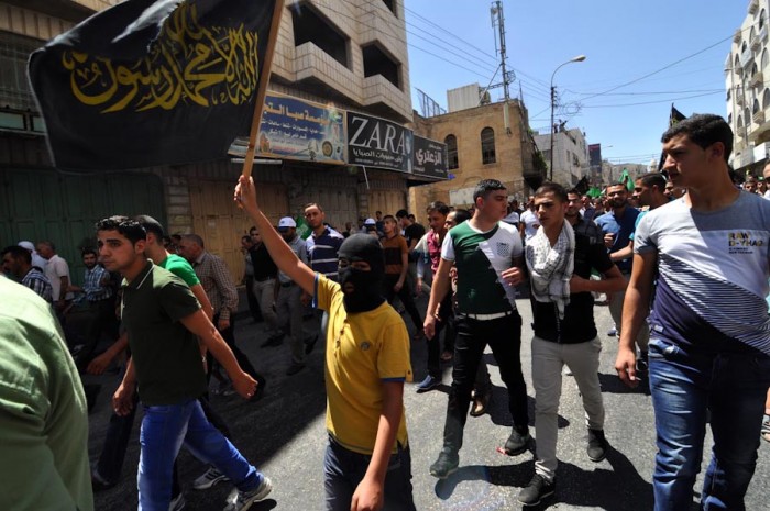 A boy waves the flag of Palestinian Islamic Jihad while marching in an August 1, 2014 protest in Hebron. The march, rallying opposition to the summer Gaza war, later turned violent and area hospitals treated at least 70 protesters for gunshot wounds. (Photo by Tom James)