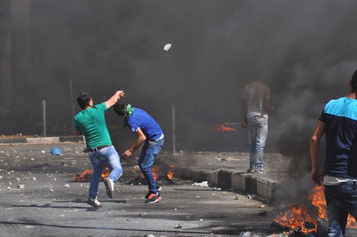 Palestinian youth throwing stones at an Israeli soldiers during a protest in Hebron in August. (Photo by Tom James)