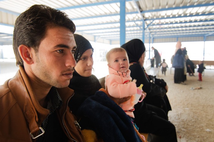 A Syrian family waits at Zaatari Refugee Camp to board a bus back across the border. According to the UNHCR, at least a hundred people return to Syria each day citing frustration with living conditions in the camp, or a desire to reunite with family, despite the risks.(Photo by Alisa Reznick)