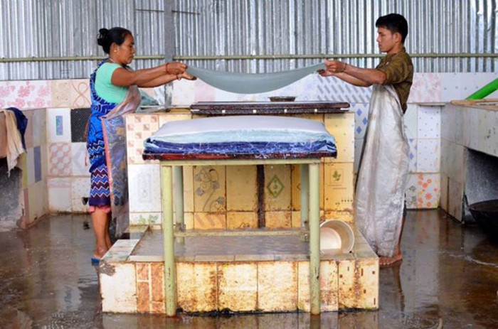Two ElRhino employees lift wet paper out of a vat. (Upaya courtesy photo)