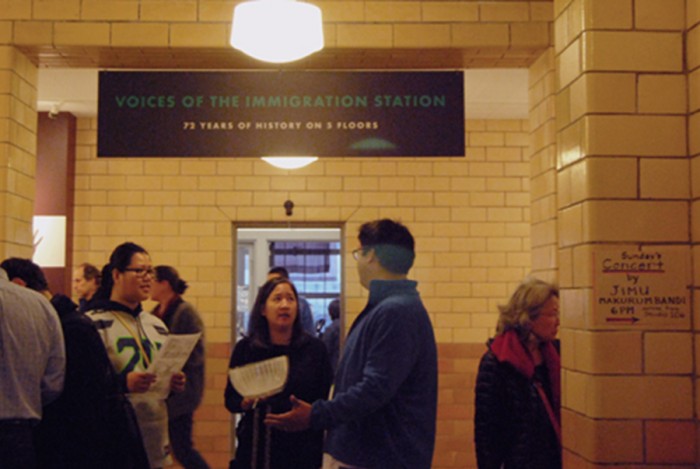 Cassie Chinn, deputy director of the Wing Luke Museum, center, talks with visitors during the opening night of “Voices of the Immigration Station.” (Photo by Ana Sofia Knauf)