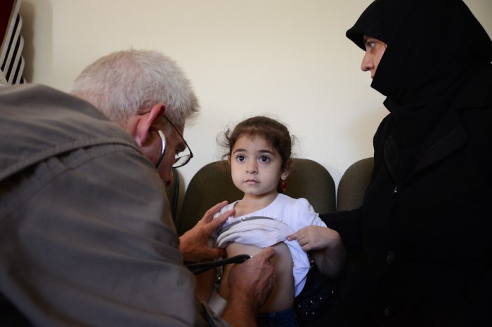 A volunteer doctor working with the Salaam Cultural Museum examines a Syrian refugee child. (Photo by Alisa Reznick)