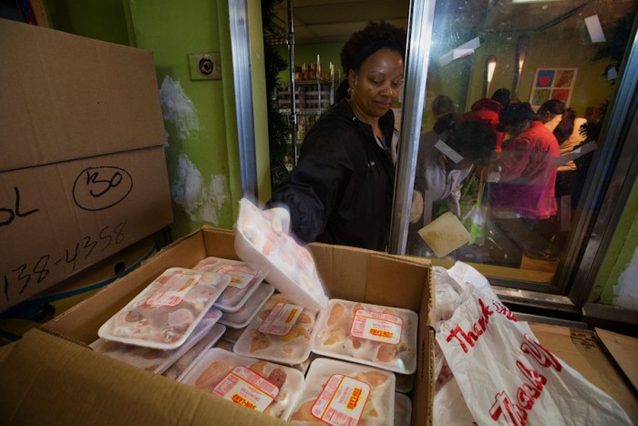 Calise Wiggins, a volunteer at Rainier Valley Food Bank, grabs some chicken drumsticks for a guest. The meat distribution was reorganized, thanks to a Japanese corporate philosophy called Kaizen, which means “good change.” (Ellen M. Banner/The Seattle Times)