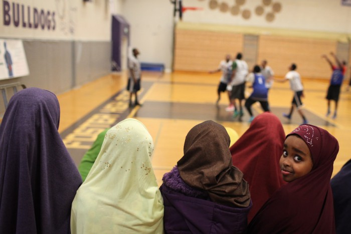 Naima Abdi, 6, watches her siblings play in an all East African basketball league in Tukwila. Somali American parents and community leaders are organizing opportunities like these for youth in South King County, but a new study shows they're still falling behind their peers in school. (Photo by Alex Stonehill)