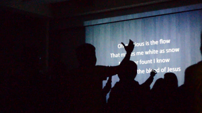Students lift their hands as they sing worship songs. (Photo by Monica Chon)