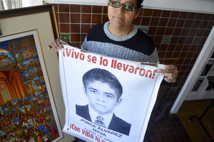 Blanca Luz Nava Vélez holds a poster of her missing son, Jorge Alvarez Nava, which reads "They took him alive!" (Photo by Janelle Retka)