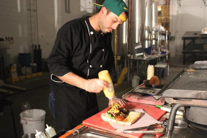 Chalisea applies the finishing touches to a Lomo Saltado Sandwich. (Photo by Cristy Acuña)