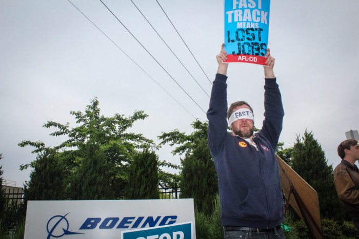 Garett Scott, a letter carrier and member of the AFL-CIO, pickets before a visit by Secretary of State John Kerry at the Boeing Co.'s Renton plant. (Photo by Venice Buhain.)