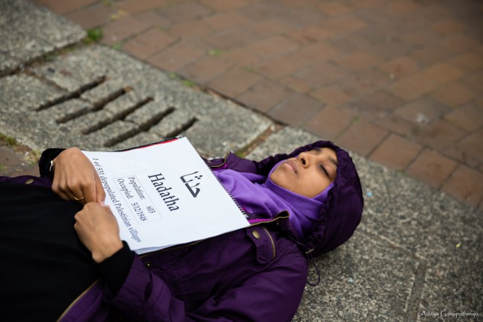 Fethya Ibrahim, a junior at UW, participates in a die-in on Red Square representing the depopulated Palestinian village Hadatha. Each of about 50 participating students had a similar sign with the name of a depopulated Palestinian village written in English and Arabic. (Photo by Aditya Ganapathiraju)