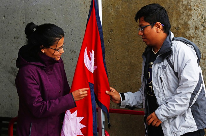 Krishna Rizal, at left, and Prerak Pradhan hang a Nepali flag at their fundraising booth on Red Square at the University of Washington on Tuesday May 5, 2015. Students and faculty on the UW campus are challenging themselves to raise $50,000 to go directly to rebuilding Simjung which was the town closest to last week's earthquake in Nepal
