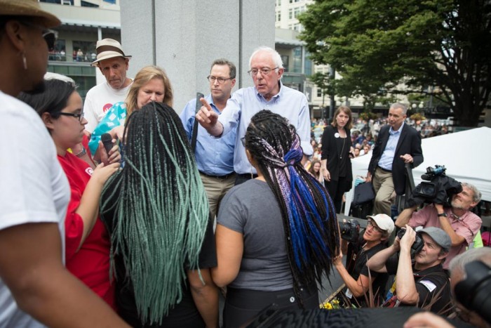 Presidential candidate Bernie Sanders talks to Black Lives Matter activists Mara Jacqueline Willaford and Marissa Johnson after they disrupted a rally at Westlake Center on Saturday where he was schedule to speak about Social Security. (Photo by Alex Garland)