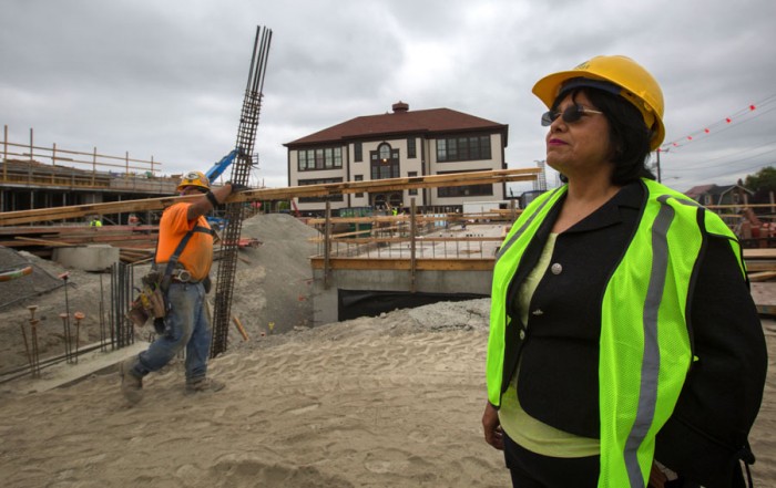 Estela Ortega, executive director of El Centro de la Raza, stands in front of one of the two buildings going up as part of a new affordable housing project on Beacon Hill. (Photo by Ellen M. Banner / The Seattle Times)