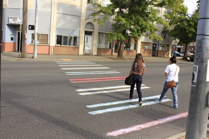 School girls crossing a a white muddled red, yellow, green painted crosswalk East-bound(Photo by Goorish Wibneh)