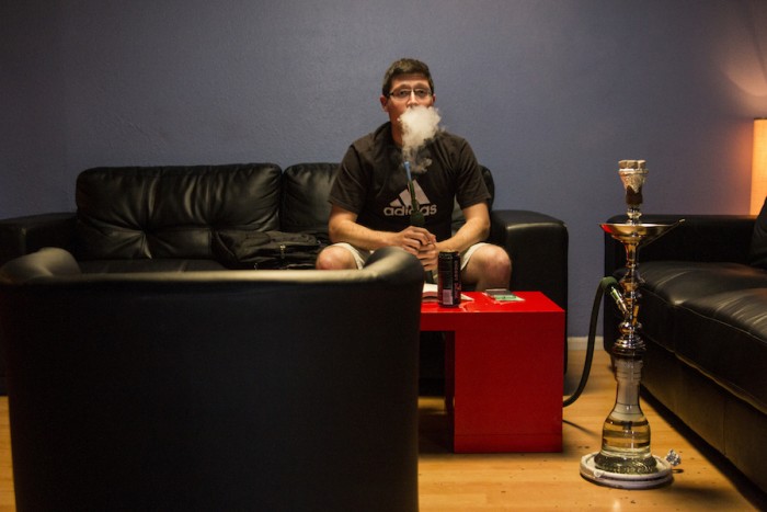 Michael Perez puffs from a shisha at Cloud 9, a hookah lounge in Seattle's Central District. (Photo by Jama Abdirahman)
