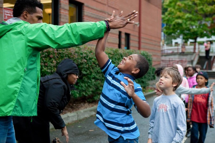 Gabriel Rapier (left) high fives a student at Leschi Elementary School on Friday, as part of #SeattleHigh5. The event aimed to show children of color positive images of black men and women in their community. (Photo by Jovelle Tamayo)