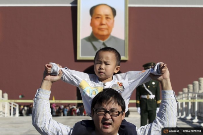 A boy sits on his father's shoulders as they pose for a photograph in front of the giant portrait of late Chinese chairman Mao Zedong on the Tiananmen Gate, in Beijing. (Photo from Reuters)