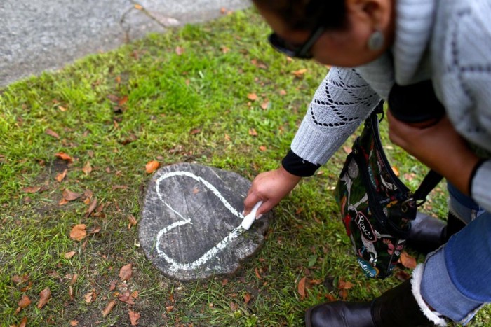 Xochitl Garcia draws a heart with chalk in front of the Amor Spiritual Center on Sunday. (John Lok/The Seattle Times)