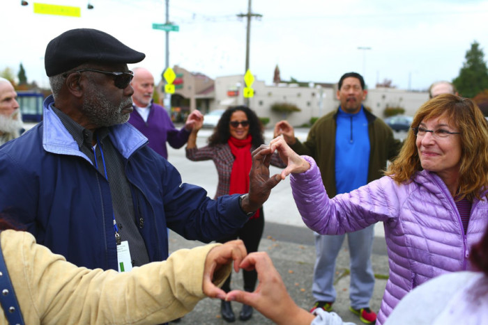 Frank Jones and Eileen Hershberg form a shape of a heart with their hands Sunday near the Amor Spiritual Center on Beacon Hill. They joined city council candidates and others in a love circle in response to hateful graffiti sprayed on the building’s front window area. (Photo by John Lok / The Seattle Times)