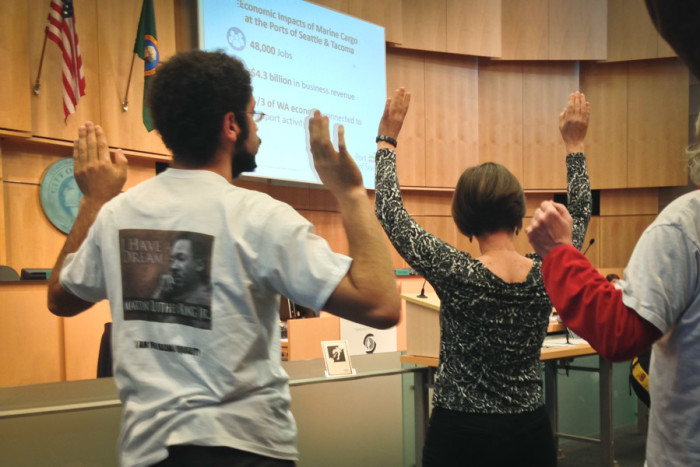Demonstrators raise their arms in protest during a January meeting of the Seattle City Council to discuss police activity in response to Black Lives Matter. (Photo by Theo Nestor)
