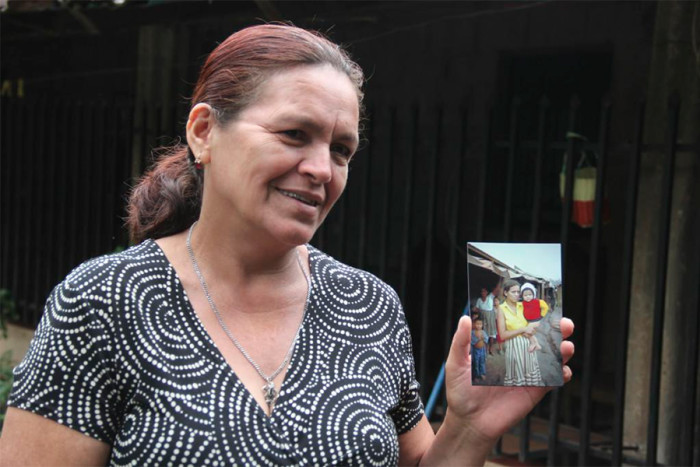 Dina Cabrera holds a photo of herself with her son taken in 1982 in the Mesa Grande refugee camp by Philippe Bourgois. Dina was five months pregnant during the November 1981 invasion. (Photo by Keny Sibrian via UW Center for Human Rights Twitter.)