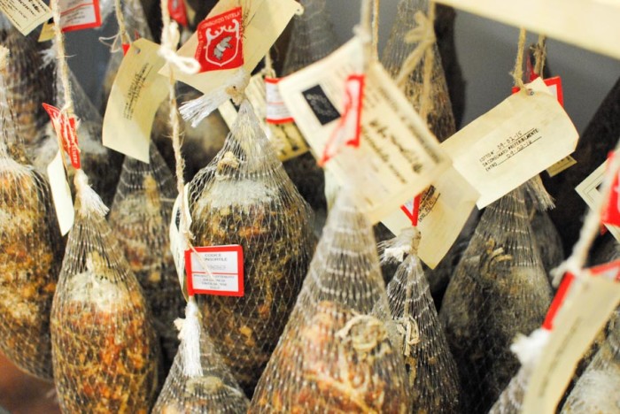 Cuts of salumi hanging at Spannocchia Foundation, tagged with special 'DOP' certification (Protected Designation of Origin), which proves that the product was made according to a specific tradition in a certain place. (Photo by Anna Goren.)