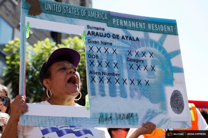 A woman holds a replica green card sign during a protest march to demand immigration reform in Hollywood. (Photo by Lucy Nicholson for Reuters/file.)