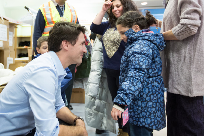 Canada Prime Minister Justin Trudeau is joined by Ontario Premier Kathleen Wynne as they hand out parts of a welcome package to newly arrived Syrian refugees. (Photo courtesy Prime Minister Justin Trudeau via Flickr.)