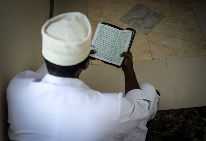 A delegate in Mogadishu reads the Koran ahead of the start of a National Conference on Tackling Extremism in Somalia in 2013. The conference drew imminent Somali scholars, elders and imams from both within the country and internationally. (Photo by Stuart Price for AU-INST photo via AMISOM Flickr.)